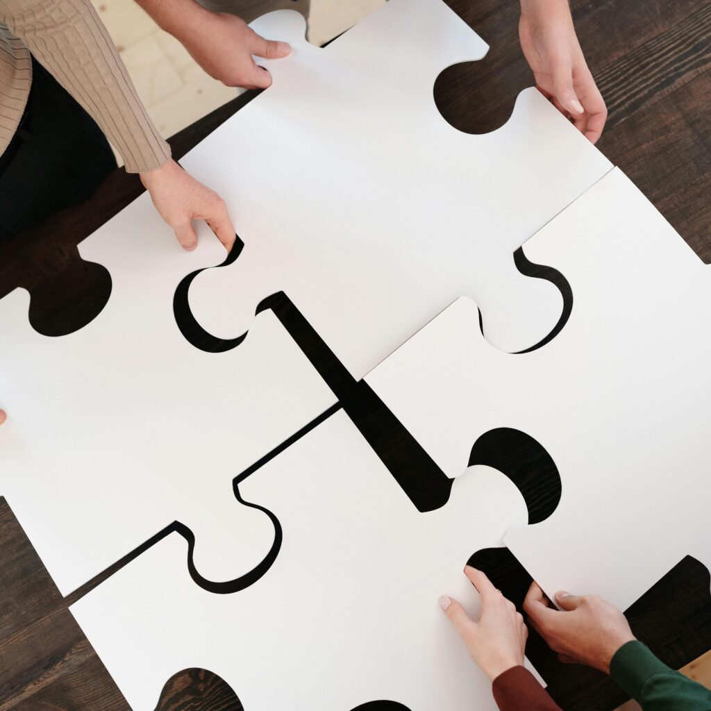 Group collaborating on assembling large puzzle pieces symbolizing teamwork and unity.